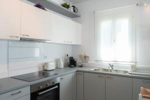 una cocina blanca con armarios blancos y fregadero en NEFELI'S GUESTHOUSE IN PLATYS GIALOS SIFNOS en Platis Yialos Sifnos
