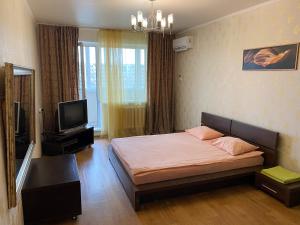 1 dormitorio con 1 cama, TV y ventana en Apartments on Ryabikova, en Ulyanovsk
