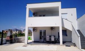 ein weißes Haus mit einem Balkon mit Stühlen in der Unterkunft Apartmani Valuna in Privlaka
