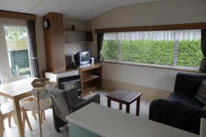 a small living room with a couch and a tv at CHALET AAN HET STRAND in Nieuwvliet