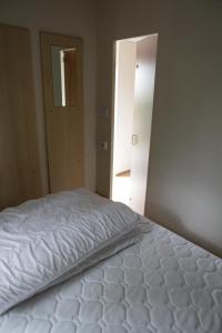 Cama blanca en habitación con puerta abierta en CHALET AAN HET STRAND, en Nieuwvliet