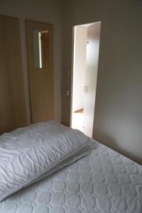 a white bed in a room with an open door at CHALET AAN HET STRAND in Nieuwvliet