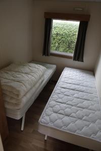 two beds in a room with a window at CHALET AAN HET STRAND in Nieuwvliet