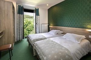 two beds in a hotel room with a green wall at Logis Hôtel Restaurant Le Mont Aigoual in Meyrueis