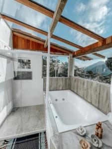 baño grande con bañera y ventana de cristal en Pousada Quinta das Nascentes, en Petrópolis