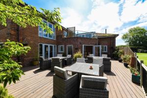 a patio with tables and chairs on a wooden deck at Lakeside Old Hunstanton in Hunstanton