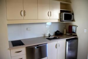 a small kitchen with a sink and a microwave at Cedar Grove Motor Lodge in Nelson