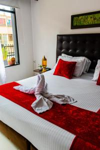 a bedroom with a large bed with red and white sheets at Central House Hotel in Bogotá