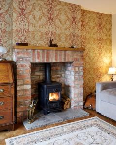 a fireplace in a living room with a stove at Maltkiln Cottage in Barbon