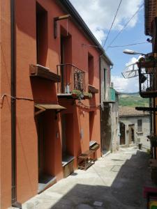 an alley with a red building with a balcony at B&B ANDEMAR Rooms in Satriano di Lucania