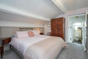a bedroom with a white bed and a wooden cabinet at Maltkiln Cottage in Barbon