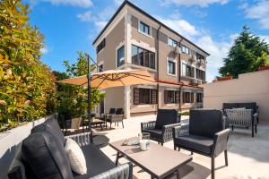 a patio with chairs and tables and an umbrella at Sunset Residence Rovinj in Rovinj