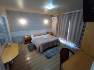 Dormitorio pequeño con cama y mesa en Pousada Ruppenthal, en Canela