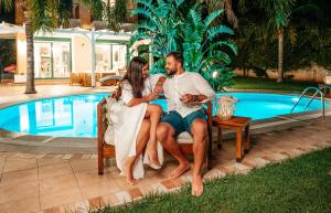 um homem e uma mulher sentados numa cadeira ao lado de uma piscina em Pandora Villas em Hersonissos