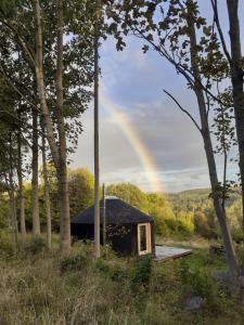 a tent in the woods with a rainbow in the background at Black Yurt Chromiec in Stara Kamienica