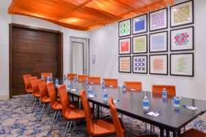 una sala de conferencias con una mesa larga y sillas naranjas en Holiday Inn Express New Orleans - St Charles, an IHG Hotel en Nueva Orleans