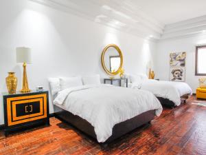 een witte slaapkamer met 2 bedden en een spiegel bij Hotel Boutique Villa Toscana in Hermosillo
