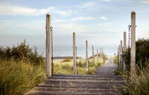 un camino de madera a la playa con postes de madera en CHALET AAN HET STRAND, en Nieuwvliet