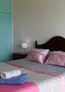 - un lit avec des oreillers roses et blancs dans l'établissement Apartamento com vista mar, à Nazaré