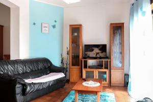 - un salon avec un canapé en cuir noir et une table dans l'établissement Apartamento com vista mar, à Nazaré