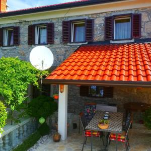 寇斯崔納的住宿－House Pelcic Kostrena，一座带桌子和椅子的橙色屋顶的房子