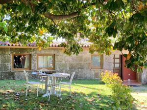 een tafel en stoelen onder een boom voor een huis bij Pedreiras Cottage Rias Baixas in Pontevedra