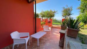 a patio with white chairs and a table and a red wall at Borgo di Santa Barbara in Santa Domenica