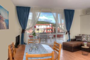 een woonkamer met een tafel en stoelen en een bank bij Privilege Beach Apartments in Sveti Vlas