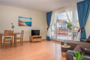 a living room with a couch and a table with a television at Privilege Beach Apartments in Sveti Vlas