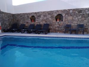 a swimming pool with chairs and a stone wall at Asteri Hotel in Ornos