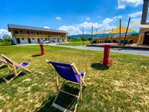 two chairs and a table in the grass in front of a building at Sport HOTEL Bečva in Valašské Meziříčí