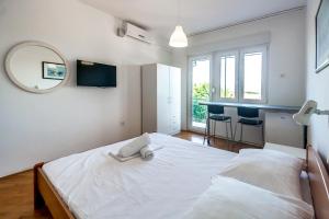 a bedroom with a large white bed with a mirror at Apartments & Rooms Strčić Krk in Krk