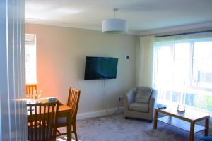 a living room with a table and a tv on the wall at Heathmere -NEC, Airport, HS2, Resorts World, Workcation - Spacious quiet apartment in Birmingham