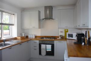 a kitchen with white cabinets and a stove top oven at Heathmere -NEC, Airport, HS2, Resorts World, Workcation - Spacious quiet apartment in Birmingham