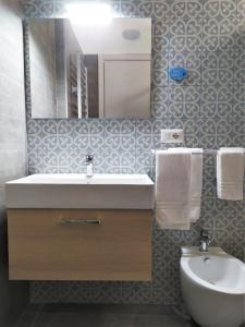 een badkamer met een wastafel, een toilet en een spiegel bij A Polignano Rooms in Polignano a Mare