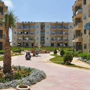 a large apartment building with a palm tree in a courtyard at Tahiti North cost تاهيتي الساحل الشمالي in Al Ḩammām