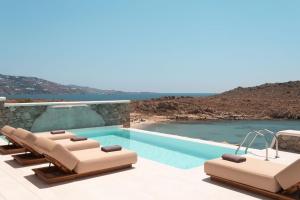 a hotel room with two lounges and a pool at Casa Del Mar - Small Luxury Hotels of the World in Agios Ioannis Mykonos