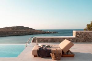 a suitcase sitting on top of a beach next to a body of water at Casa Del Mar - Small Luxury Hotels of the World in Agios Ioannis Mykonos