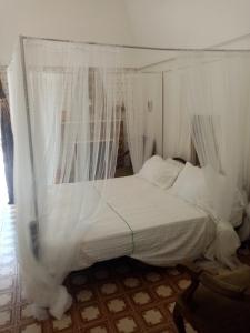 a white bed with a canopy in a room at masseria chianca " Le Gravine" in Mottola