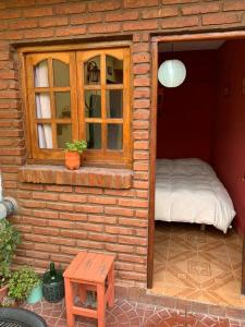 ein kleines Haus mit einem Bett und einem Fenster in der Unterkunft Malecon en calle Techada Hostel in Capilla del Monte