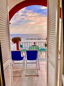 einen Balkon mit Stühlen, einem Tisch und Meerblick in der Unterkunft Hotel La Scogliera in Ischia