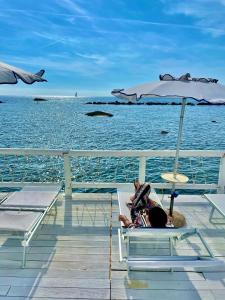 a person laying in a chair under an umbrella on the beach at Hotel La Scogliera in Ischia