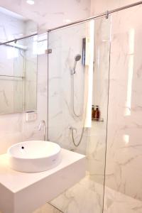 a white bathroom with a sink and a shower at Busaba Bella Hotel in Sichon