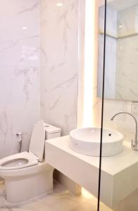 La salle de bains blanche est pourvue de toilettes et d'un lavabo. dans l'établissement Busaba Bella Hotel, à Sichon