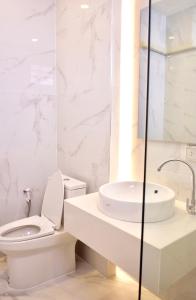 a white bathroom with a toilet and a sink at Busaba Bella Hotel in Sichon