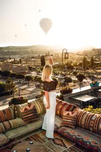 a woman standing on a ledge looking at a city at Caravanserai Inn Hotel in Goreme