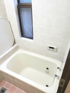 uma banheira branca na casa de banho com uma janela em Within walking distance of Disneyland! - Vacation STAY 11473 em Urayasu