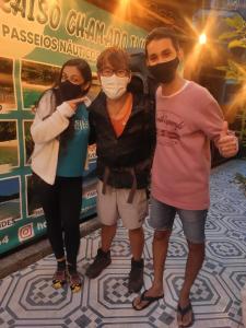Tres personas con máscaras delante de un cartel en Hostel Blue Lagoon, en Abraão