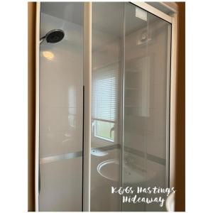 a glass shower in a bathroom with a window at Comfortable 3-Bed Caravan - Combe Haven in Hollington