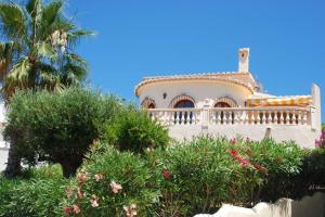 a large white house with a palm tree and bushes at Casa Helena in Moraira
